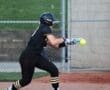 Young female softball player prepares to bunt as the pitch approaches during a game on the field.