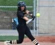 Young female softball player swinging a bat at a ball during a game on a dirt field. Energetic sports action captured.