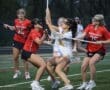 Girls’ lacrosse players competing fiercely on the field during a match, showcasing athleticism and teamwork.