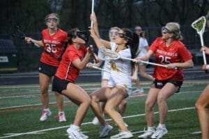 Girls’ lacrosse players competing fiercely on the field during a match, showcasing athleticism and teamwork.