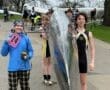 Rowing team members pose with a sleek boat before a competition, showcasing excitement and team spirit.