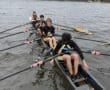 Rowing team in sync on the water, showcasing teamwork and athleticism on a cloudy day.