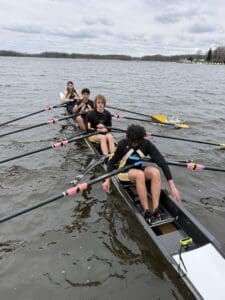 Rowing team in sync on the water, showcasing teamwork and athleticism on a cloudy day.