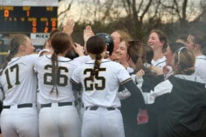 Girls’ softball team celebrating a play, showcasing teamwork and excitement with smiles and high fives.