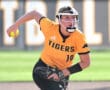 Softball player in a yellow Tigers jersey prepares to pitch, holding a softball in a sunny outdoor setting.