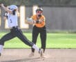 Softball players in action; one attempts to steal second base as the fielder prepares to make the catch.