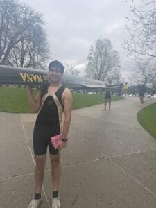 Rower carrying a boat on a pathway, showcasing athletic gear and teamwork in a scenic outdoor setting.