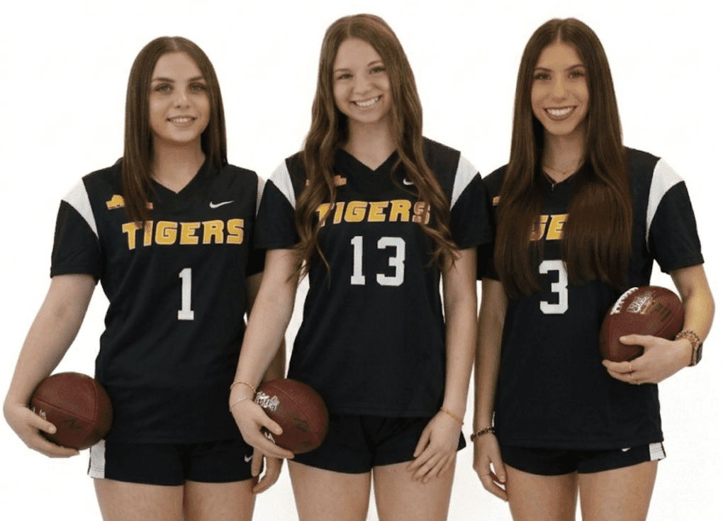 Three female athletes in black Tiger uniforms pose with footballs, showcasing team spirit and strength.