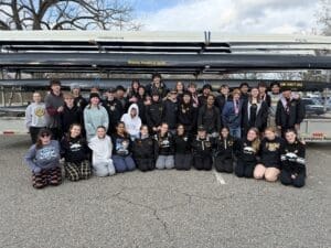 Rowing team group photo with medals, showcasing teamwork and spirit at the Allegheny River.