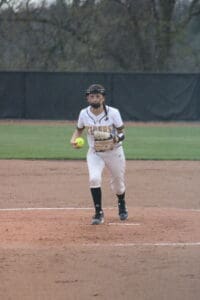Softball player in a Tigers jersey prepares to pitch on a field, showcasing athletic action and team spirit.