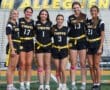 Six female athletes in black jerseys and yellow belts pose together on a sports field, showcasing team spirit for the Tigers.