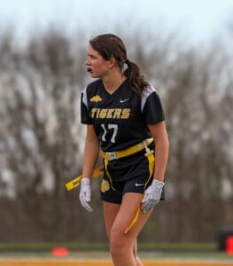 Female flag football player in a Tigers uniform, focused on the game, with a determined expression and yellow belt.