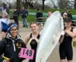 Rowing team members pose with their boat and race number 149 at a competition on a cloudy day.