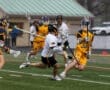 High school lacrosse players compete on a rain-soaked field, showcasing action and teamwork during the game.