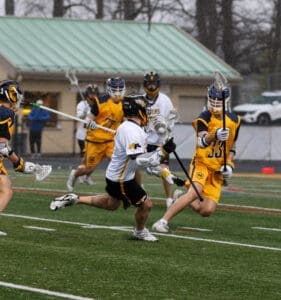 High school lacrosse players compete on a rain-soaked field, showcasing action and teamwork during the game.