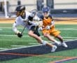 Two young lacrosse players compete on the field, showcasing action and skill in an intense game.
