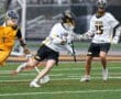 High school lacrosse players in action on the field, showcasing athleticism and teamwork during a game.