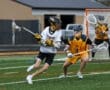 High school lacrosse players compete on the field, showcasing athleticism and strategy in a dynamic game action.