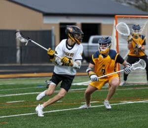 High school lacrosse players compete on the field, showcasing athleticism and strategy in a dynamic game action.