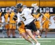 Tigers lacrosse player dodges opponent on the field during a game, showcasing dynamic athleticism and teamwork.