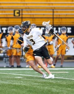 Tigers lacrosse player dodges opponent on the field during a game, showcasing dynamic athleticism and teamwork.