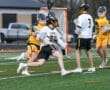 Boys' lacrosse players in a dynamic play on the field, showcasing teamwork and competition in action.