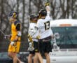 Teenage lacrosse players celebrate a goal during a match, showcasing teamwork and sportsmanship on the field.