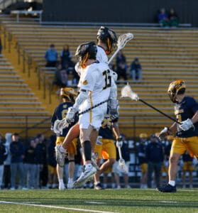 Lacrosse players jumping to celebrate during a game, showcasing teamwork and athleticism on the field.