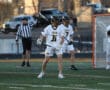 High school lacrosse players in action, focusing on teamwork and strategy during a game on a turf field.