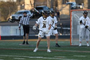 High school lacrosse players in action, focusing on teamwork and strategy during a game on a turf field.