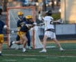 High school lacrosse players compete fiercely at the goal during a dynamic game, showcasing athletic skill and teamwork.
