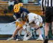 Two lacrosse players compete for the ball during a game, showcasing intensity and athleticism on the field.