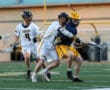High school lacrosse players compete fiercely, showcasing athleticism on the field during an intense match.
