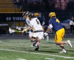 High school lacrosse players compete on the field, showcasing athleticism and teamwork during a nighttime game.