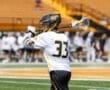 Young lacrosse player in action, wearing jersey number 33, practicing on a sunny field during a game.