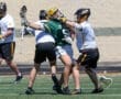 Lacrosse players in action, battling for possession on the field during a sunny day, showcasing athleticism and teamwork.