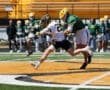 Two lacrosse players compete for the ball on a sunny field, showcasing athleticism and teamwork during a game.