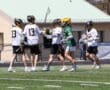 Lacrosse players in team jerseys celebrate on the field, showcasing teamwork and athleticism during a match.