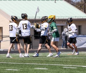 Lacrosse players in team jerseys celebrate on the field, showcasing teamwork and athleticism during a match.