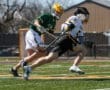High school lacrosse players racing down the field during an intense match on a sunny day.