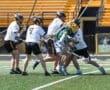 High school lacrosse players compete fiercely on the field, showcasing teamwork and athleticism during a match.