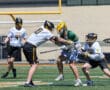 High school lacrosse players engage in a competitive game on a sunny field, showcasing athleticism and teamwork.