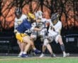 Two lacrosse teams competing fiercely during a game at twilight, showcasing teamwork and athleticism on the field.