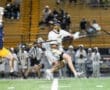 Lacrosse players compete in a dynamic match under stadium lights, showcasing athleticism and teamwork on the field.