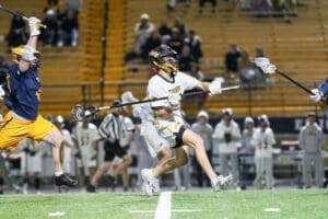 Lacrosse players compete in a dynamic match under stadium lights, showcasing athleticism and teamwork on the field.