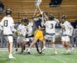High school lacrosse players engaged in an intense game, with action and teamwork on the field during a nighttime match.