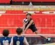 Young male volleyball player diving to receive a ball over the net during a match at Peters Township gym.