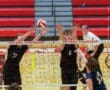 Boys volleyball players attempting a block during a match at Peters Township High School gymnasium.