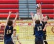 A high school volleyball match with players jumping at the net to block a spike. Excitement fills the gym.