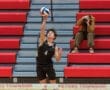 High school volleyball player #4 serves the ball during a match, with fans in the background capturing the moment.